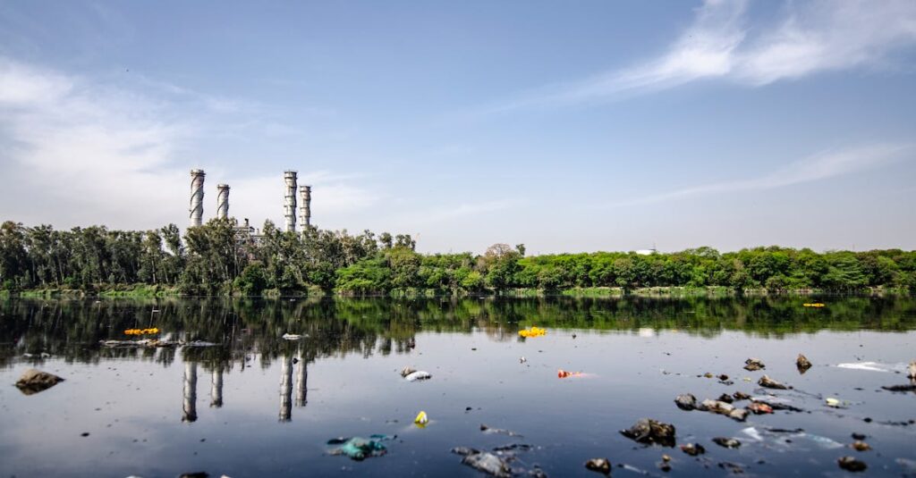 View of a polluted river reflecting factory emissions under a clear sky in India.