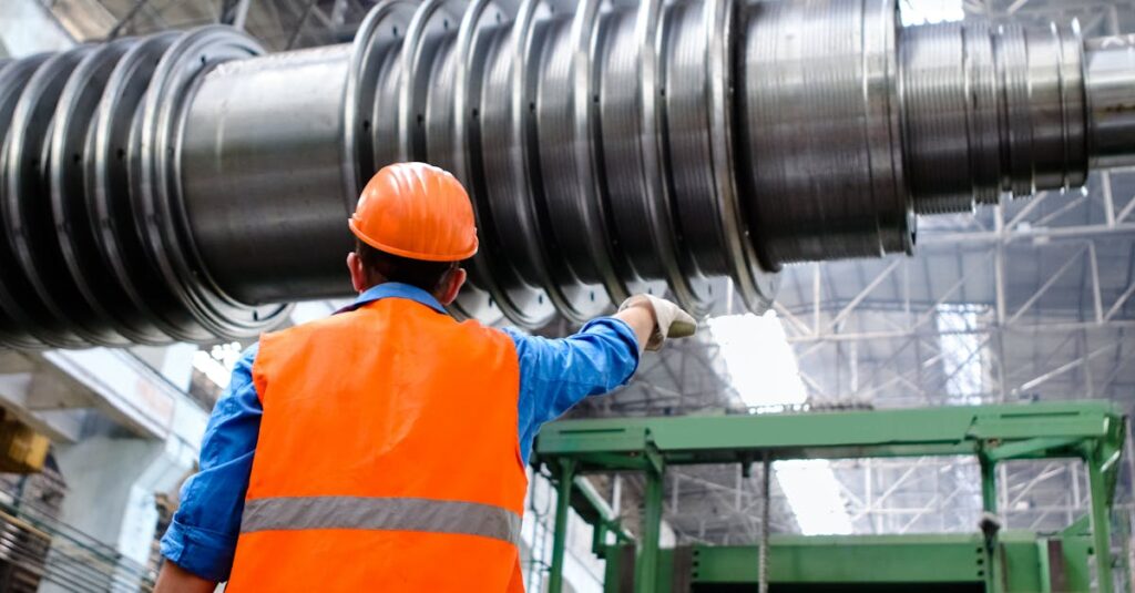 Engineer in high visibility vest and hard hat inspecting large machinery in factory setting.